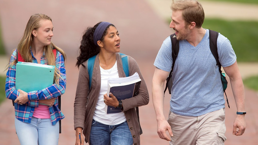 Students talk as they walk through campus.